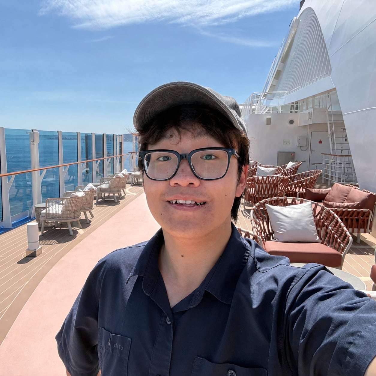 Portrait of Sheng Wan outdoors on a ship deck under a blue sky.